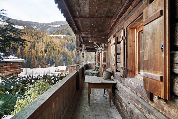 A wooden cabin with a balcony overlooking a snowy landscape.