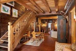 A rustic interior with a wooden staircase, a dining area, and a sofa.