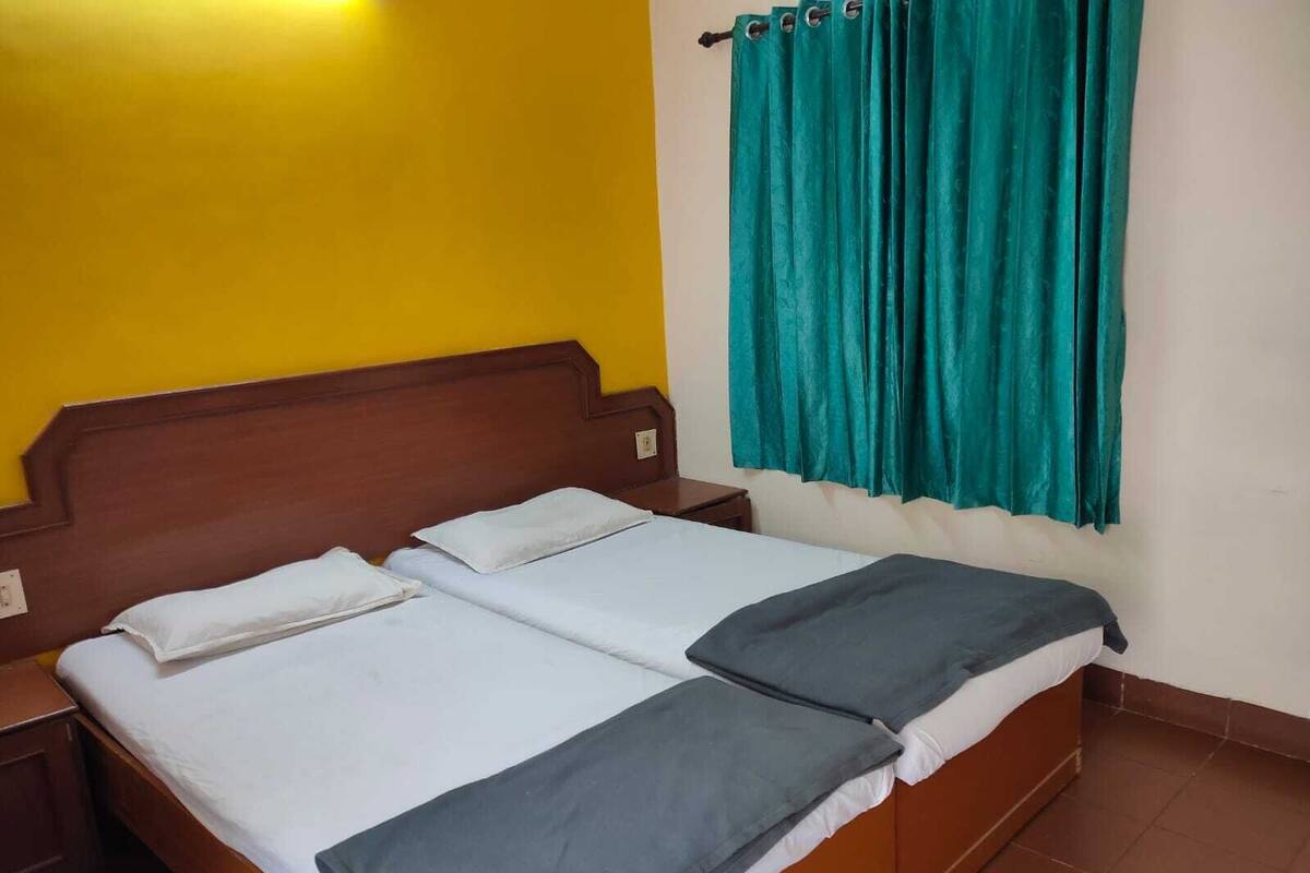 A single bed with a wooden headboard, white bedding, and a teal curtain.