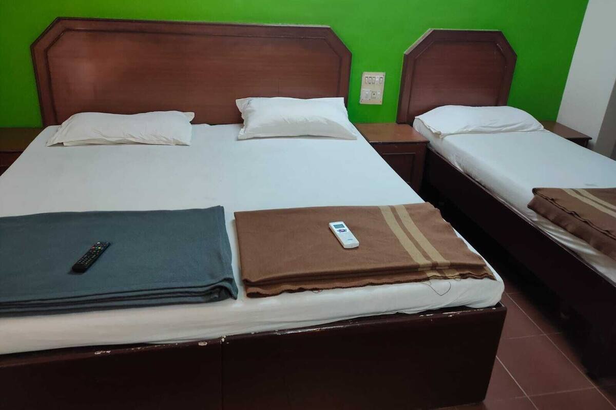 A hotel room with two beds, a green wall, and a wooden headboard.