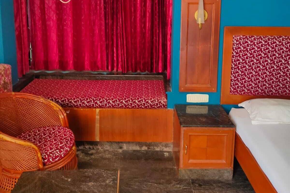 A room with a bed, a wooden cabinet, a wicker chair, a red curtain, and a hanging lamp.