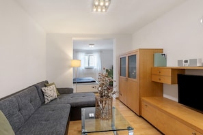 A modern living room with a sofa, a glass coffee table, a wooden cabinet, and a television.