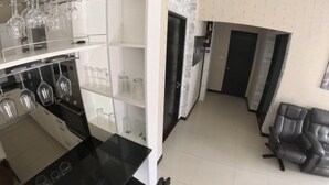 A kitchen with wine glasses and glassware on shelves, a black countertop, and a black chair in the dining area. - Beautiful pool villa 200 meters from the beach and the beach promenade 4 bedrooms (Bang Saray)