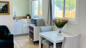 A modern kitchen with a built-in microwave, a dining table with chairs, and a view of the outdoors through large windows.