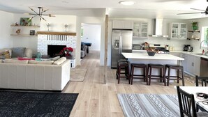 A modern kitchen with white cabinets, a built-in island, and a dining area with bar stools. - Apple Farm Paradise in Julian (Julian)
