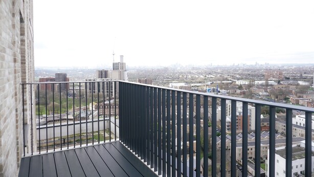 Ein Balkon mit Blick auf eine Stadtlandschaft, mit einer Mischung aus Wohn- und Geschäftsgebäuden.