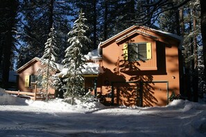 Eine Holzhütte mit Garage, umgeben von schneebedeckten Bäumen.