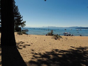 Ein Strand mit freiem Blick auf das Wasser, Boote und ferne Berge.