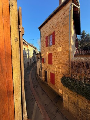 A narrow street with stone buildings, wooden fences, and red shutters. - THE DOVE NEST Centre of Medieval Figeac - leave the car behind! (Figeac)