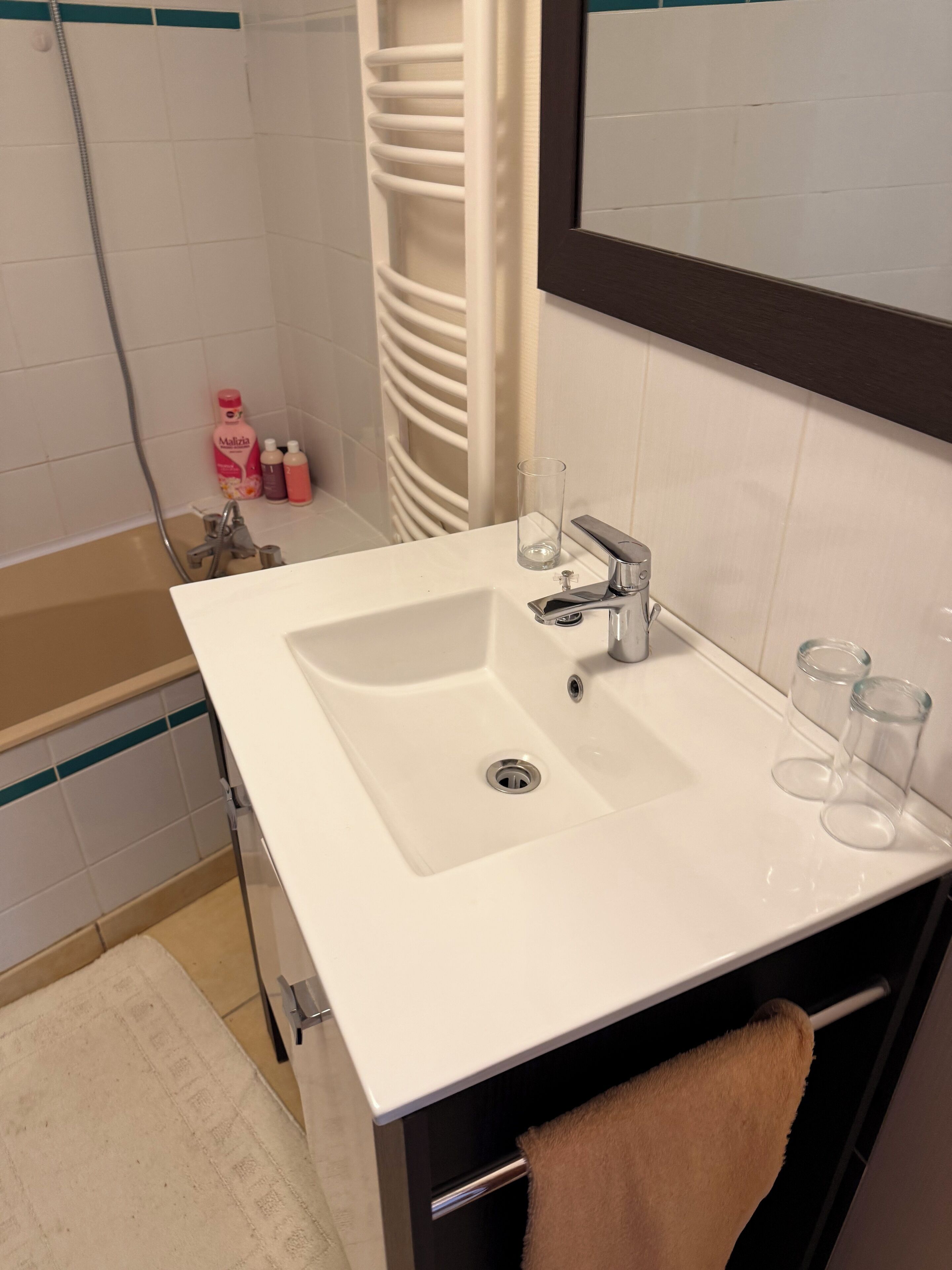 A bathroom with a white sink, a mirror, and a towel rack.