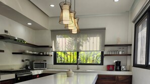 A modern kitchen with a large island, built-in appliances, and a view of greenery through the window.
