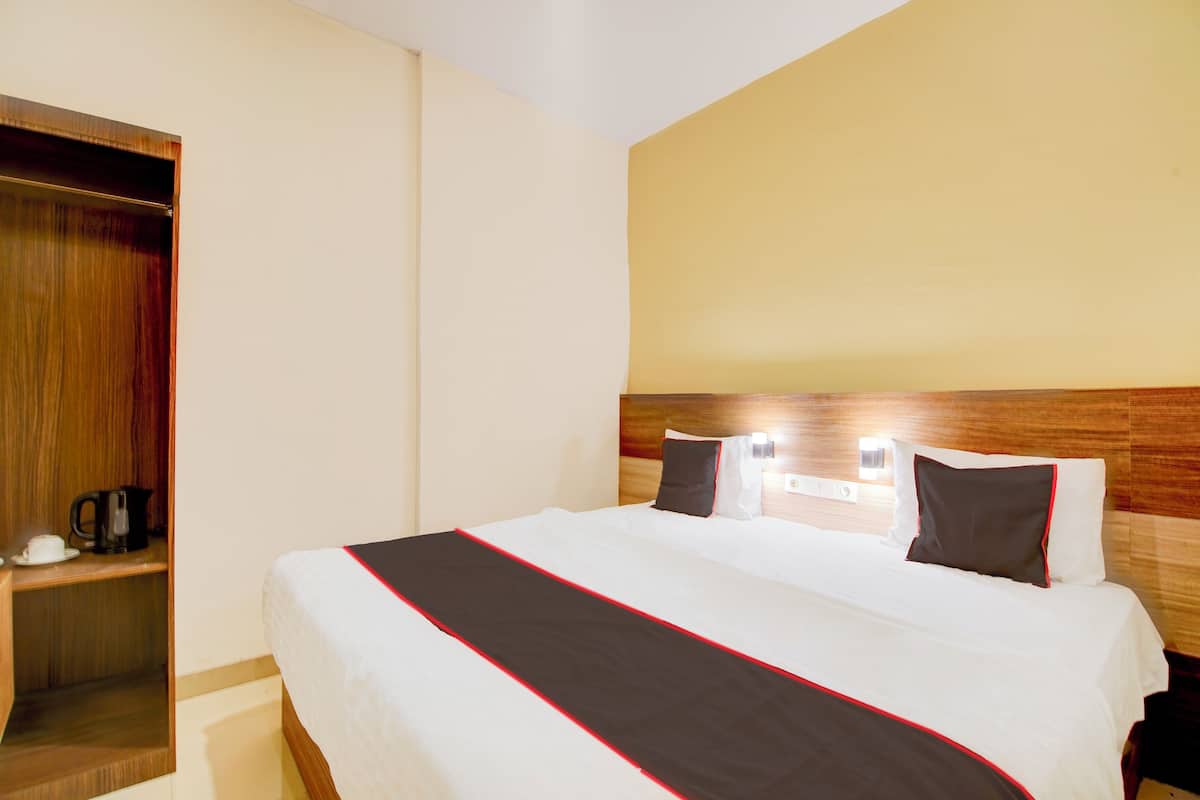 A hotel room with a bed, bedside table, and a wardrobe.
