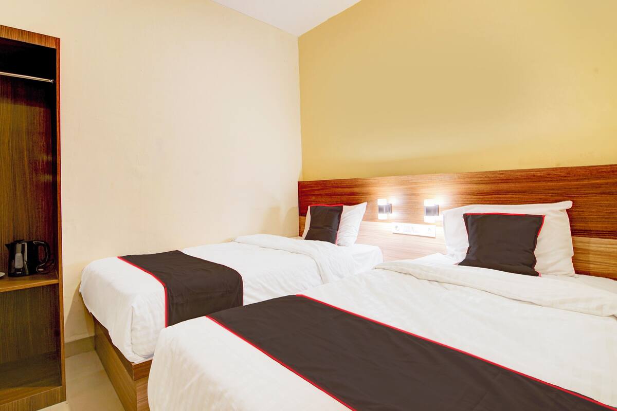 A hotel room with two beds, wooden headboards, and a shelf with a coffee maker.