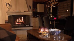 A cozy living room with a fireplace, wooden furniture, and a laptop on a table. - Nesset Fiskfjord. House by the sea with panoramic views, Gateway to Lofoten! (Troms)