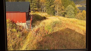 A view of a mountainous landscape with a red building and a wooden bridge. - Nesset Fiskfjord. House by the sea with panoramic views, Gateway to Lofoten! (Troms)
