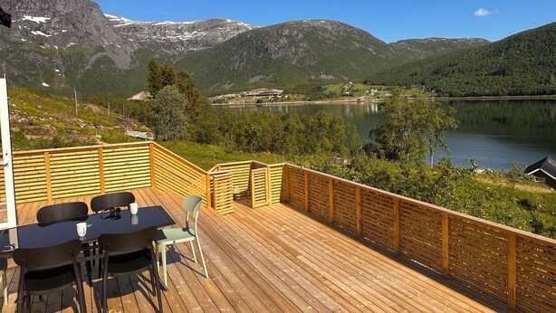 A wooden deck with a table and chairs overlooking a lake and mountains. - Nesset Fiskfjord. House by the sea with panoramic views, Gateway to Lofoten! (Troms)