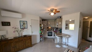 A modern kitchen with a central island, white bar stools, and a ceiling fan. - Swimming pool, air conditioning, 200 m from beaches, ideal for family holidays (SIX FOURS LES PLAGES)