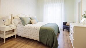 A bedroom with a bed, bedside tables, a dresser, a mirror, and a window with curtains.