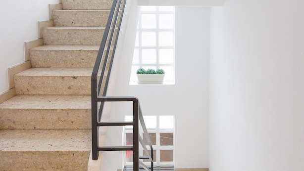 A staircase with a black handrail leading to a landing.