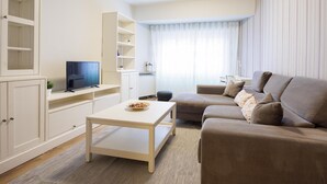 A modern living room with a sofa, a coffee table, a TV, and built-in shelving.