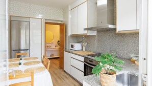 A modern kitchen with white cabinets, a stainless steel range hood, a microwave, and a granite countertop.