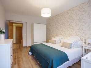 A bedroom with a bed, a nightstand, a dresser, and a door leading to another room. - Piso 2 Adeinés Viviendas Uso Turístico medio (A Estrada)