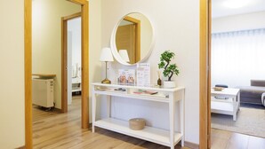 A reception area with a white console table, a round mirror, a lamp, a small potted plant, and a sign.