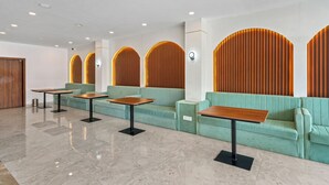 Un vestíbul modern amb sofàs verds, taules de fusta i il·luminació empotrada.