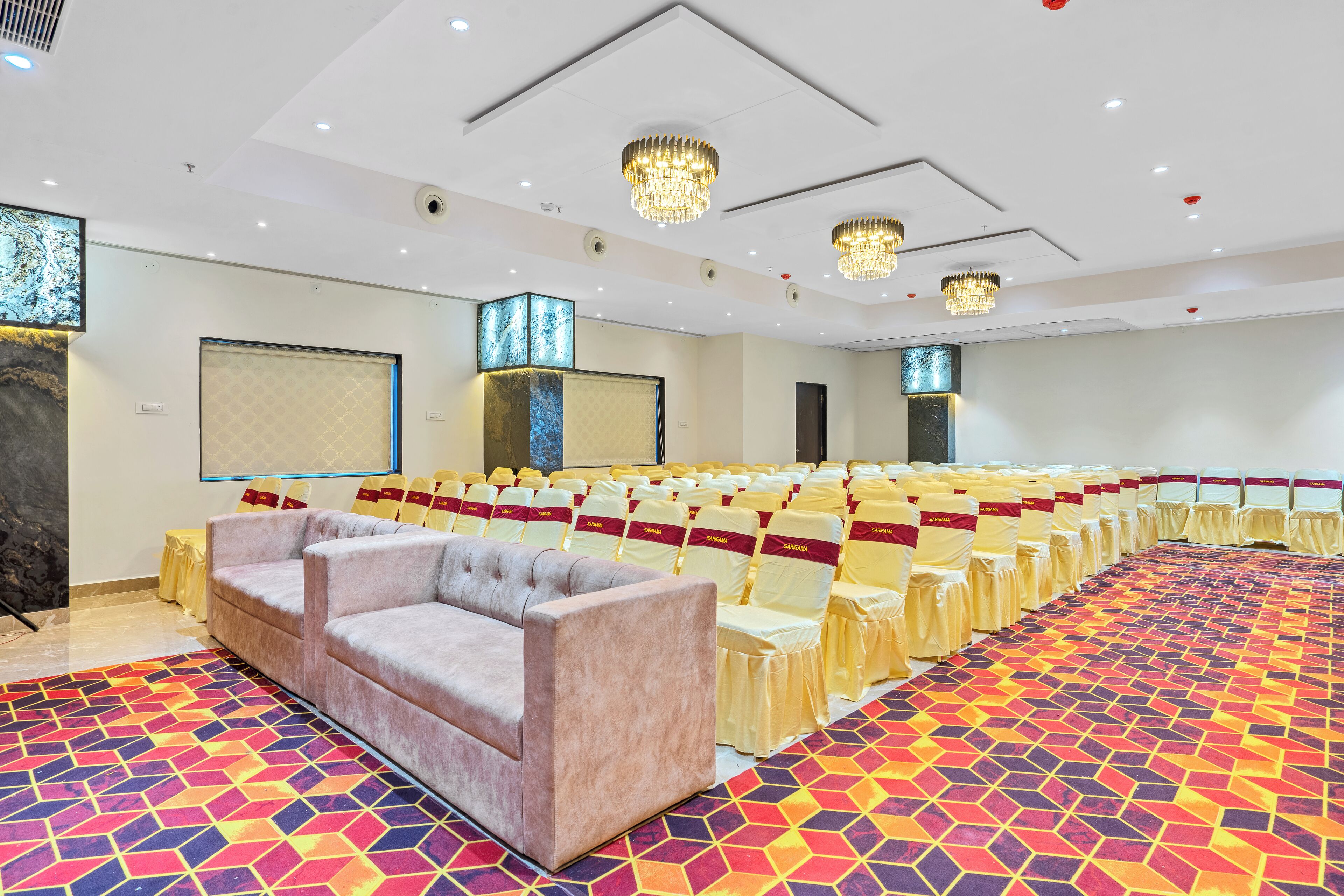 A conference room with rows of chairs, a sofa, and a patterned carpet.