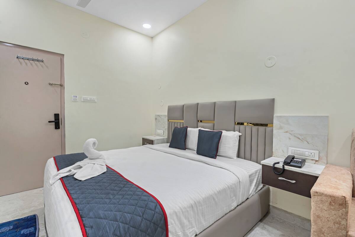 A hotel room with a bed, bedside table, and a door.