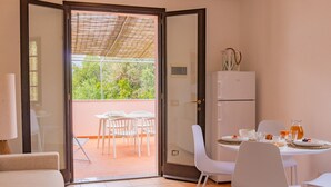 Una habitación con puerta corrediza de vidrio que da a un patio exterior con mesa lista para comer.