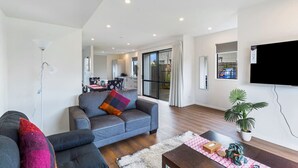 Un salon moderne avec un canapé gris, une table basse et un téléviseur fixé au mur.