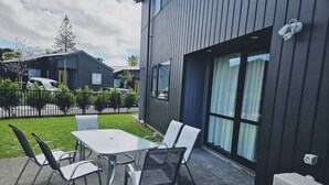 Un espace extérieur aménagé avec une table et des chaises, un bâtiment moderne doté de grandes fenêtres et une caméra de surveillance fixée au mur.