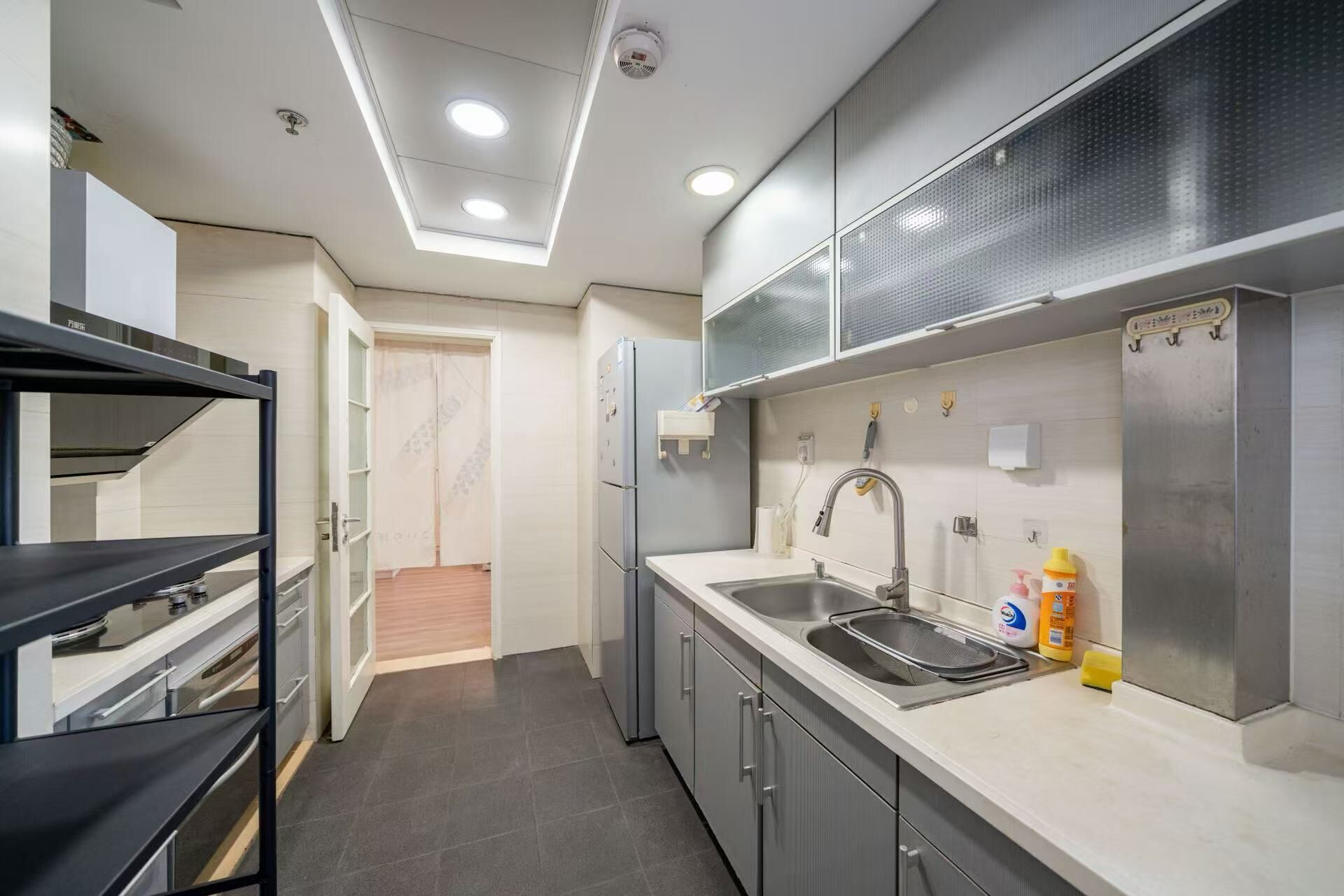 A modern kitchen with a built-in oven, a stainless steel sink, and a refrigerator.