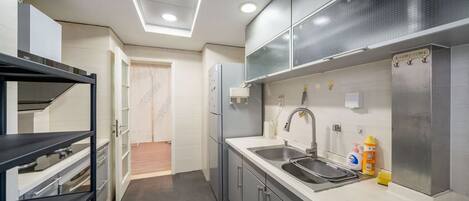 A modern kitchen with a built-in oven, a stainless steel sink, and a refrigerator.