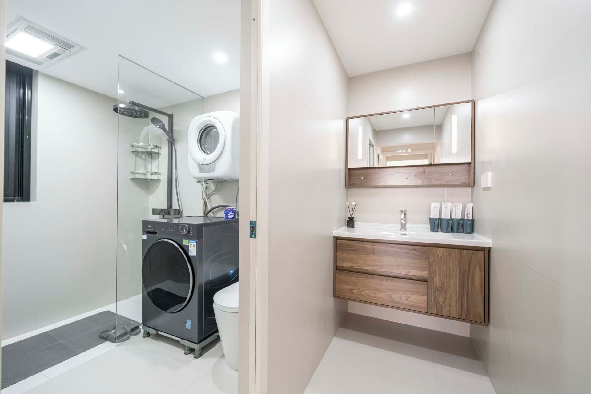 A modern bathroom with a built-in washer and dryer, a vanity with a mirror, and a toilet.