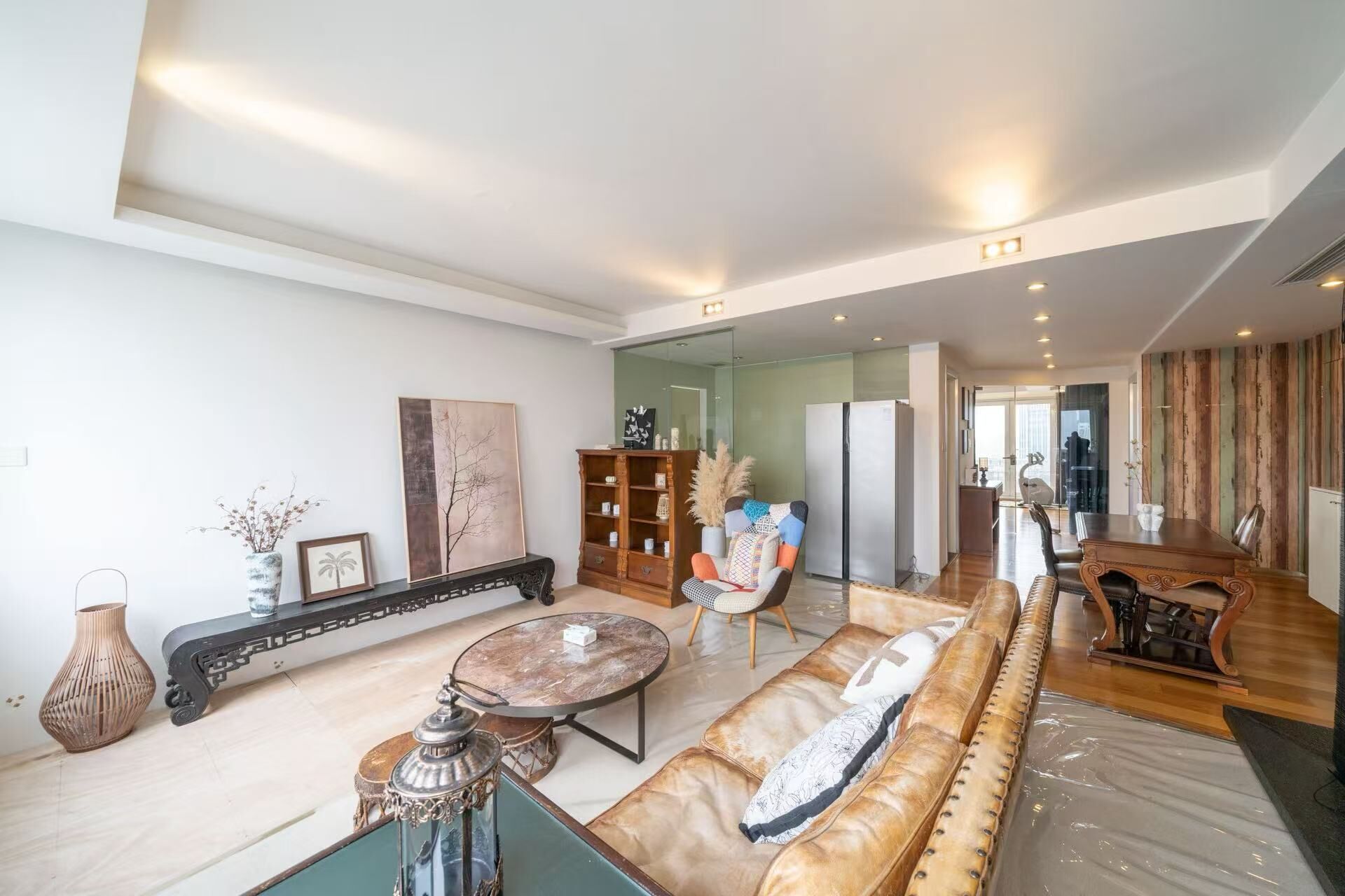 Amplia sala de estar con sofá, mesa de centro y lámpara decorativa. Se observa una estantería y una silla al fondo.