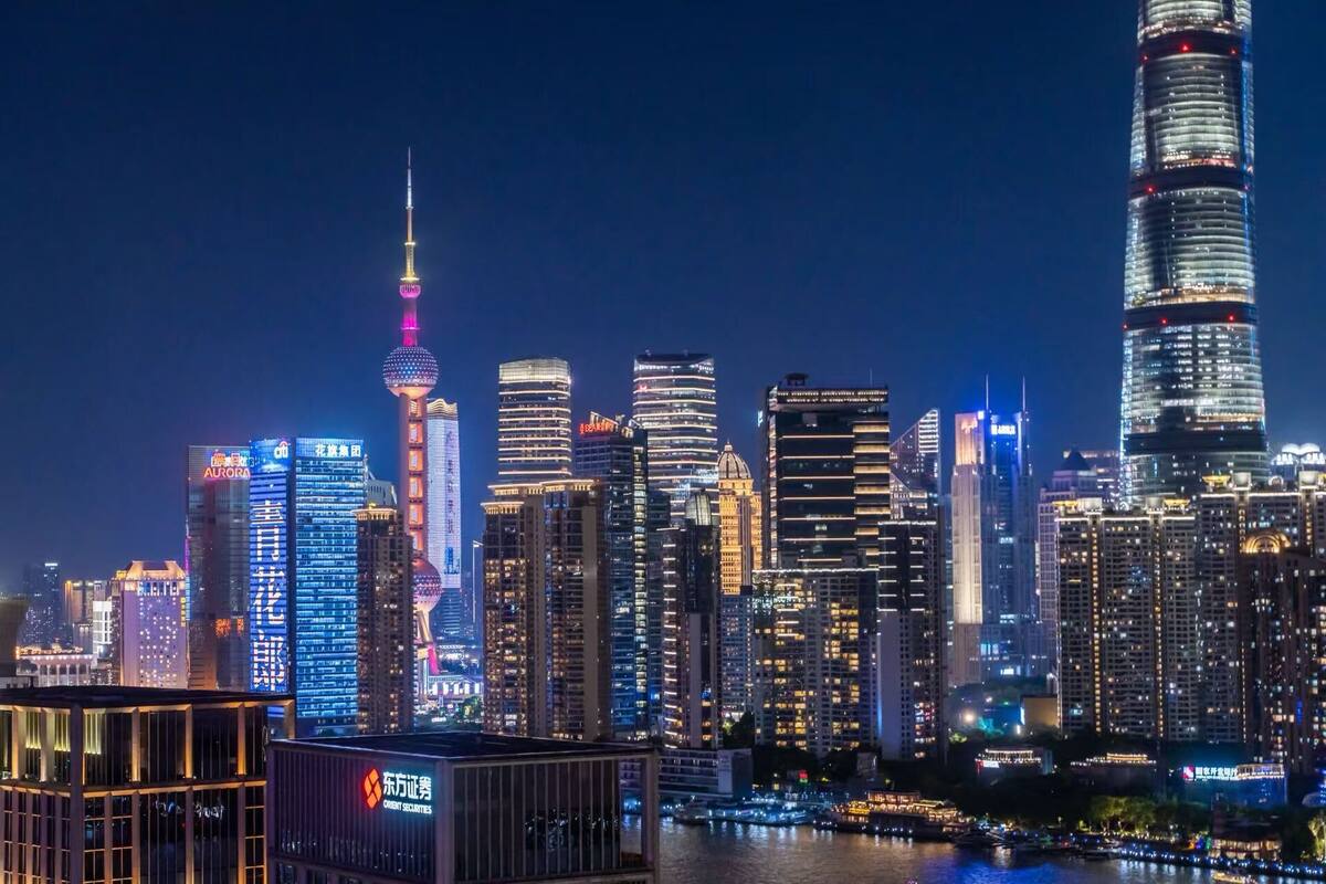 A city skyline at night with illuminated skyscrapers and a prominent tower with a spire.