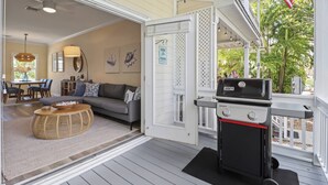 A covered porch with a grill, a dining area with a table and chairs, and a living room with a sofa and decorative pillows. - Coral Oasis – Spacious 3BR Retreat, Shared Pool, Dog Friendly, Parking, Minutes to Downtown Key West (Key West)