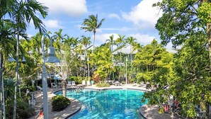 A pool surrounded by palm trees and lounge chairs, with a clear blue sky above. - Coral Oasis – Spacious 3BR Retreat, Shared Pool, Dog Friendly, Parking, Minutes to Downtown Key West (Key West)