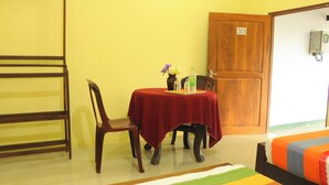 A room with a wooden door marked with the number 503, a bed with a colorful bedspread, a table with a red tablecloth, and a chair. - Leon Lakeside Hotel (Sella Kataragama)