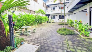 A courtyard with a paved walkway, potted plants, and a stone table. - Collection O at Jalan Padma near Legian Beach (Legian)