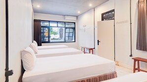 A hotel room with two beds, a window with curtains, a wall-mounted air conditioner, and a door with a curtain. - Collection O at Jalan Padma near Legian Beach (Legian)