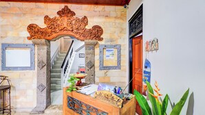 A reception desk with a wooden finish, a staircase, and a stone wall. - Collection O at Jalan Padma near Legian Beach (Legian)