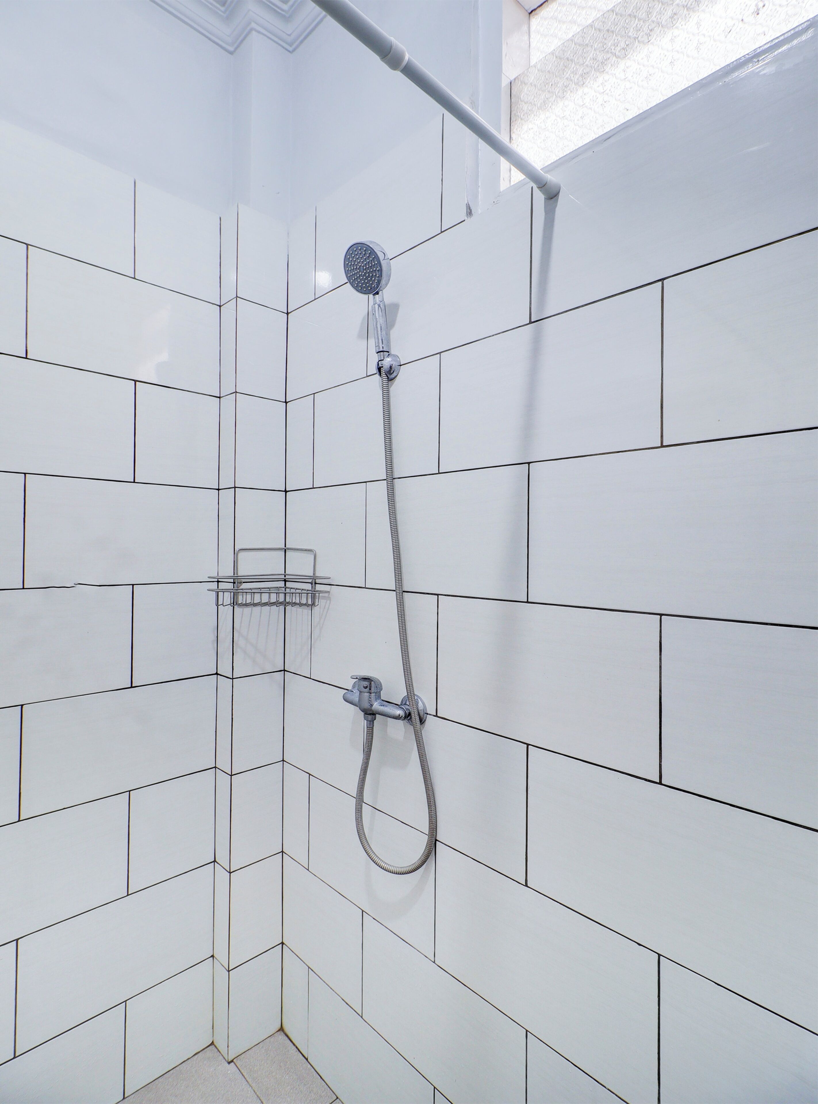 A shower with a handheld showerhead and a wall-mounted control.