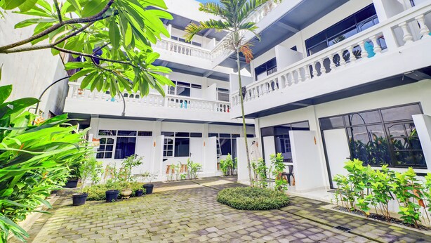 A multi-level courtyard with potted plants, a central circular garden, and a white building with balconies. - Collection O at Jalan Padma near Legian Beach (Legian)