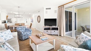 Un salon moderne avec un téléviseur, un canapé et un coin repas.