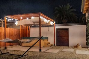 A covered outdoor seating area with a hammock, wooden deck, and string lights. - Hot Tub*3bd2ba*Backyard*King*1.2Gbps*pooltable (El Centro)
