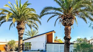 A modern house with a garage, palm trees, and a clear sky.