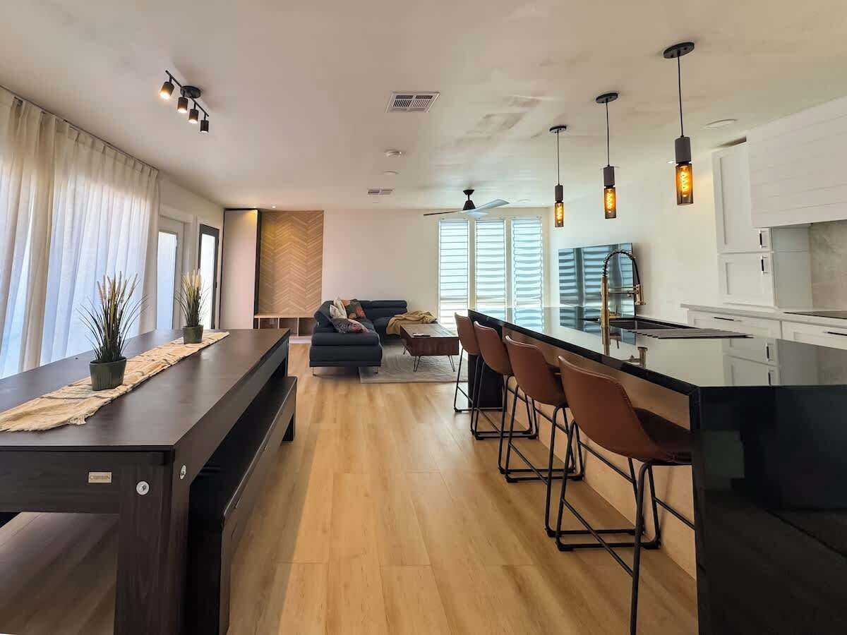 A modern kitchen with a bar area, wooden flooring, and pendant lighting.